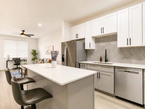 A modern kitchen with white cabinets, a stainless steel refrigerator, and a hexagonal tile backsplash. - CozySuites Glendale - Westgate w pool! 1BR 1BA (Glendale)