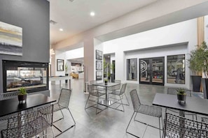 Amplio espacio interior con mesa de billar, zona de estar con sillas y ventanas grandes que ofrecen vistas al gimnasio.