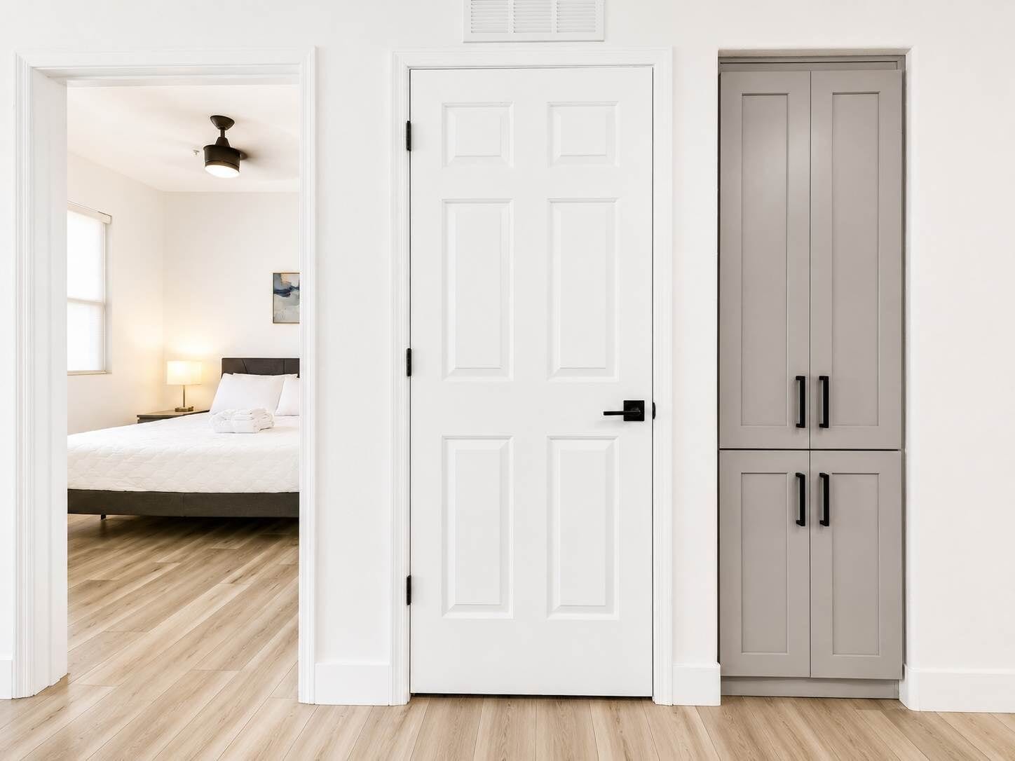 Een hotelkamer met een bed, een bedlampje en een garderobe met twee deuren.