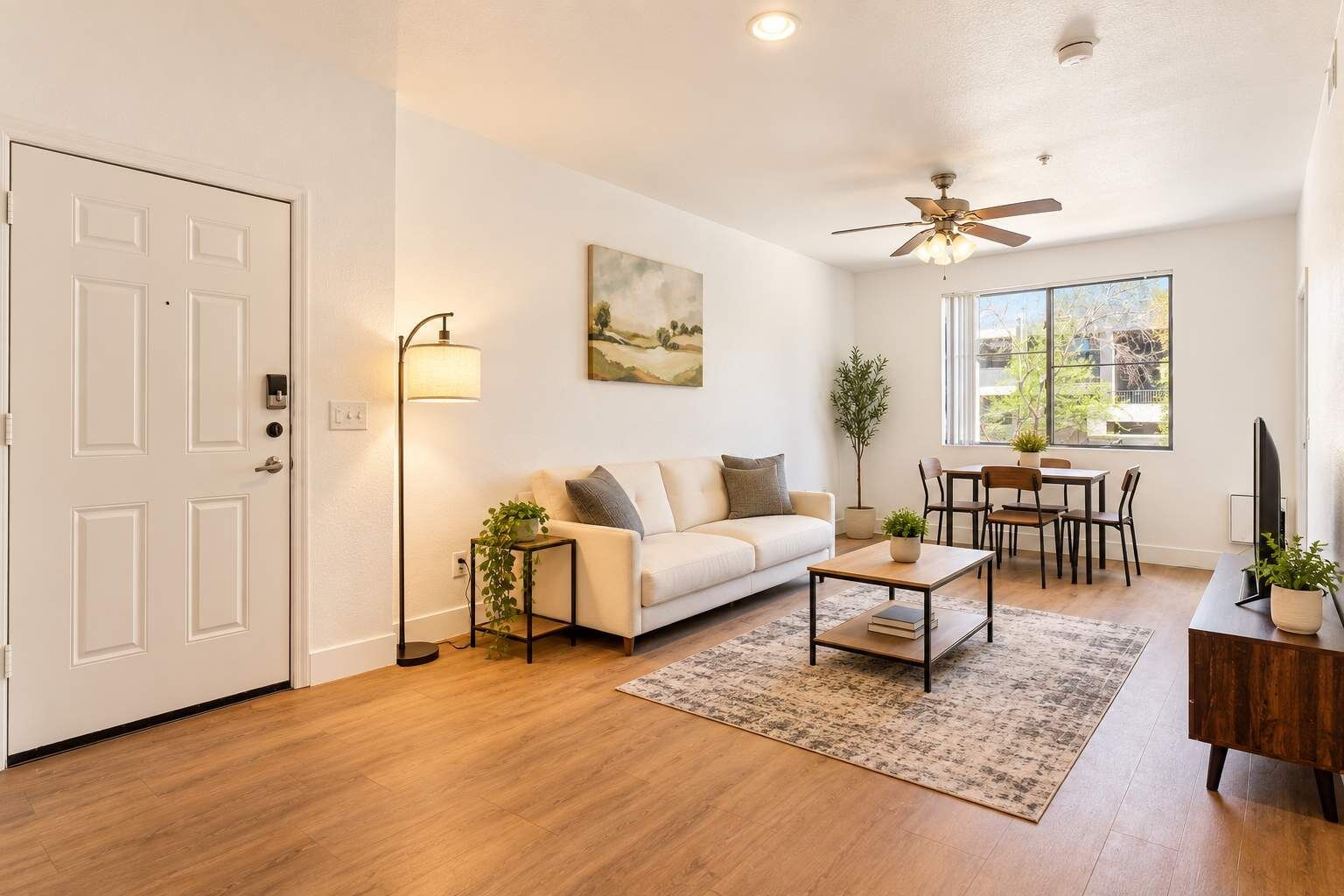 A living room with a sofa, coffee table, and a dining area with chairs and a table.