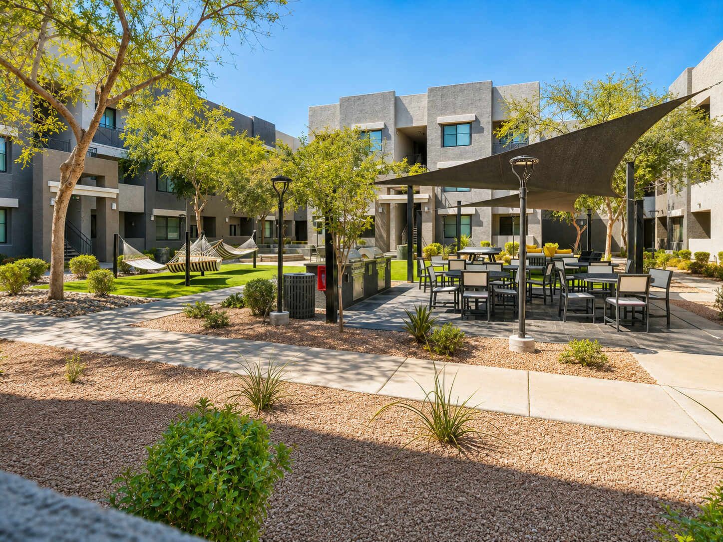 A courtyard with outdoor seating, trees, and a building with multiple windows.
