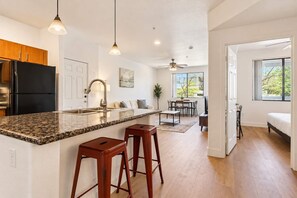 A modern kitchen with granite countertops, stainless steel appliances, and a bar stool. - CozySuites Glendale - Westgate w pool! 1BR 1BA (Glendale)