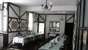 A dining area with multiple tables, chairs, and chandeliers. - Standard Triple Room (Blackpool)