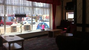 A room with a large window, a table, a chair, and a small table. - Standard Triple Room (Blackpool)