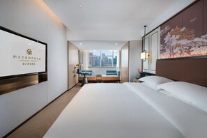 Habitación de hotel con una cama grande, un escritorio, una silla y vistas a la ciudad.