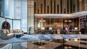 A modern lobby with a reception desk, seating area, and large windows.