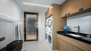 A modern laundry room with a washing machine, a drying rack, and a sink.