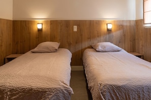 Una habitación con dos camas individuales, cada una con una almohada y una mesita de noche.