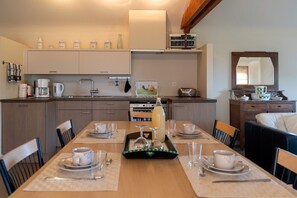 A modern kitchen with a dining area set for four, including a coffee maker, kettle, and a radio. - Apartment 3 – Enjoy a cozy stay at the Alfonsinehoeve (Horpmaal)