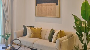 A living room with a beige sofa, a coffee table, a potted plant, and a framed artwork on the wall. - King Size Bed| PrivateBBQ| CapCana| Beach Juanillo (Punta Cana)