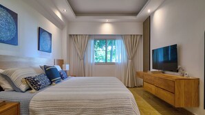 A modern bedroom with a large bed, a TV, and a wooden dresser. - King Size Bed| PrivateBBQ| CapCana| Beach Juanillo (Punta Cana)