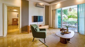 A modern living room with a green armchair, a coffee table, and a flat-screen TV mounted on the wall. - King Size Bed| PrivateBBQ| CapCana| Beach Juanillo (Punta Cana)