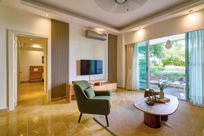 Una sala de estar moderna con un sillón verde, una mesa de centro y un televisor de pantalla plana montado en la pared.