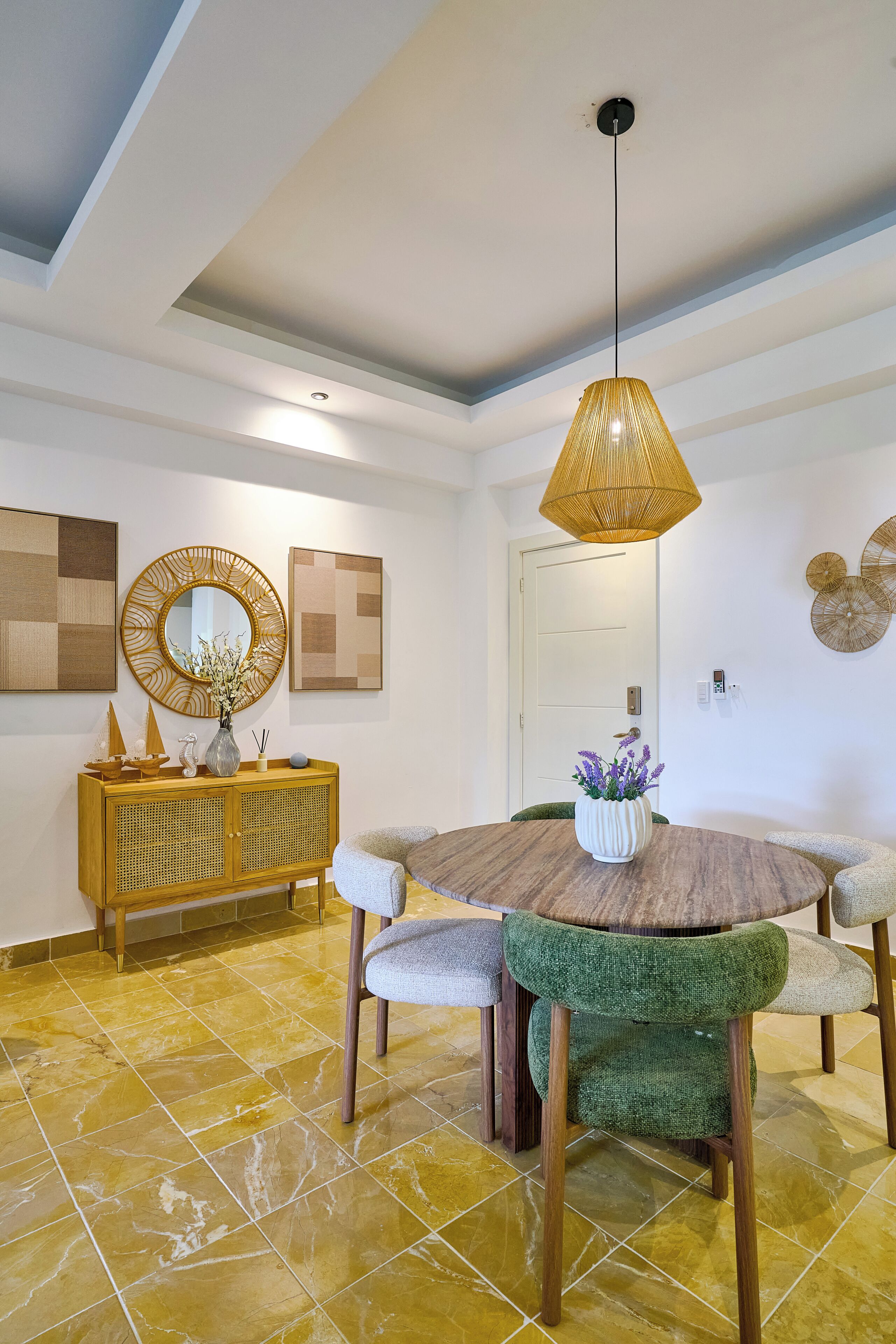 Un coin repas comprenant une table ronde, des chaises, un meuble en bois, un miroir et des œuvres d’art murales.