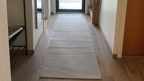 A hallway with a wooden floor, a patterned rug, a metal rack, and a view of the outdoors through a glass door. - Solvang Ferienhaus mit Fjordblick & privatem Garten (Møre og Romsdal)