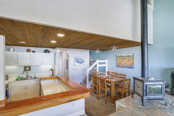 A kitchen with a wooden countertop, white cabinets, and a dining area with a wooden table and chairs.