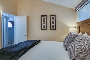 A hotel room with a bed, a nightstand, a lamp, and two framed pictures on the wall.