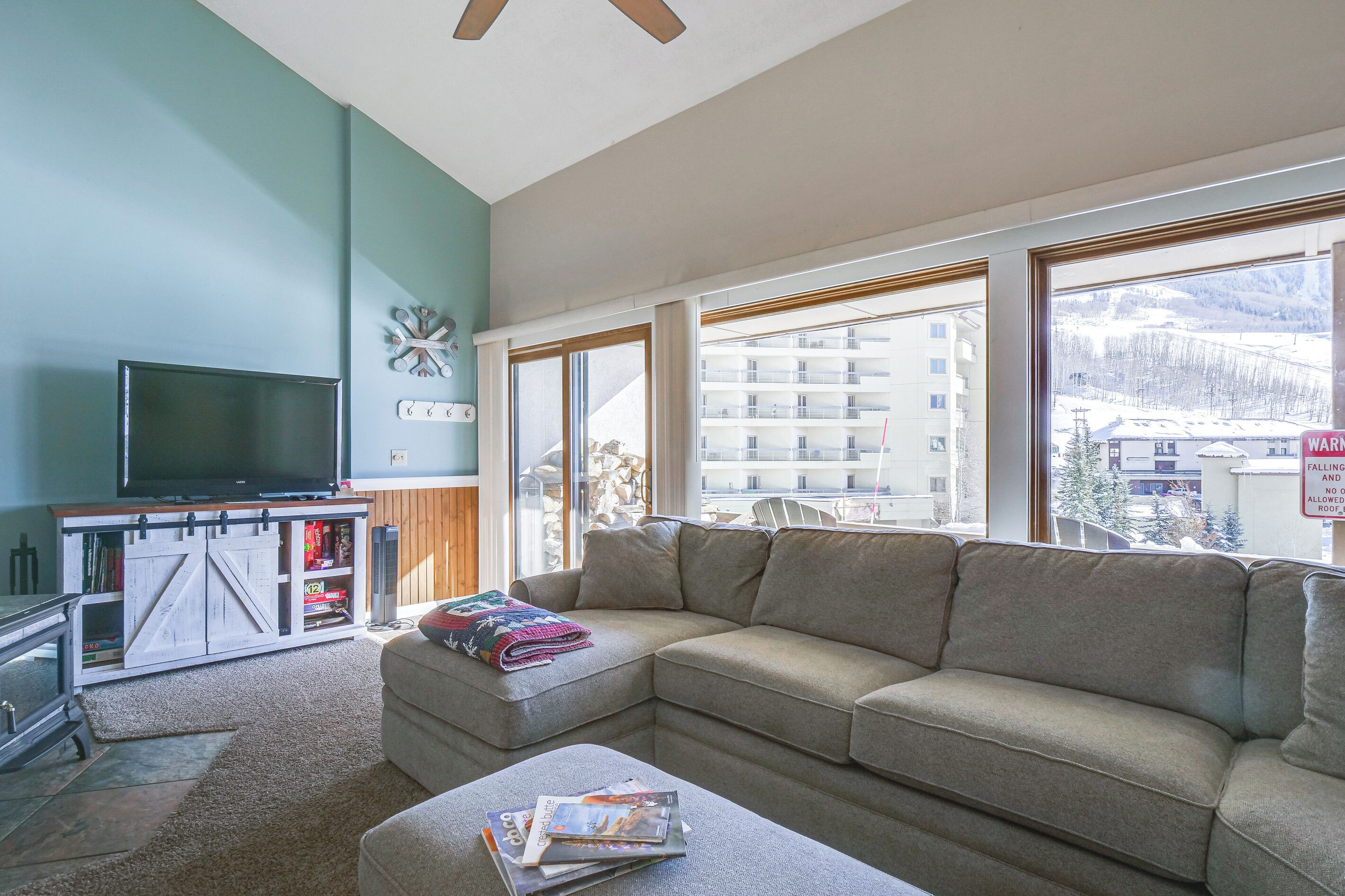A living room with a large window, a television, and a sofa.