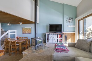 A cozy living room with a fireplace, a dining area, and a large window.