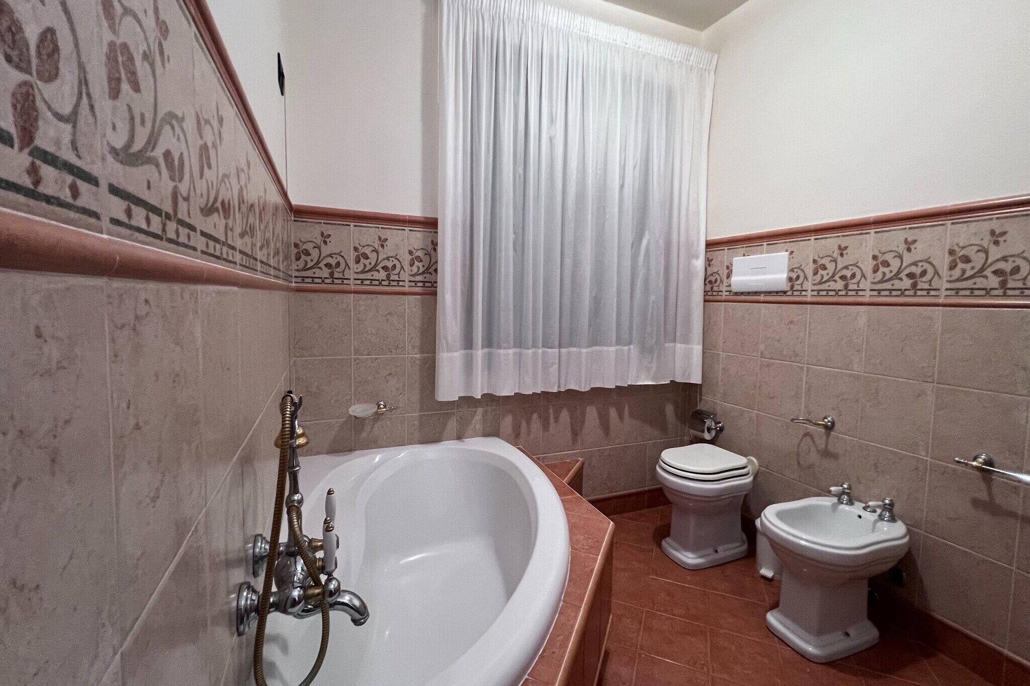 A bathroom with a bathtub, two toilets, and a bidet.