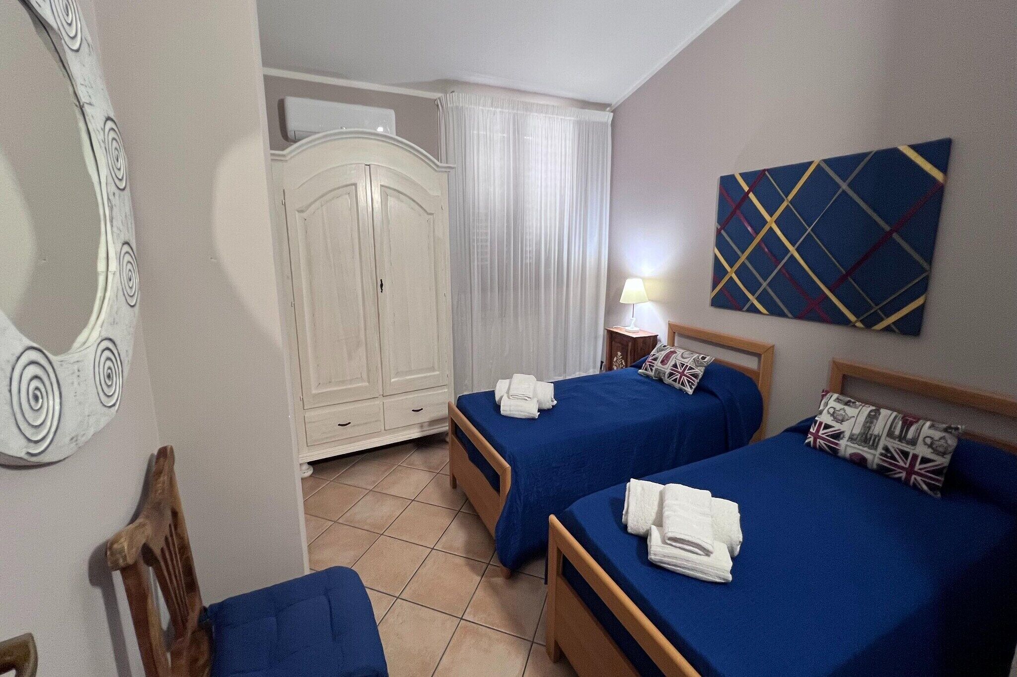 Une chambre d’hôtel avec deux lits, une armoire, un miroir, un tableau et une lampe.
