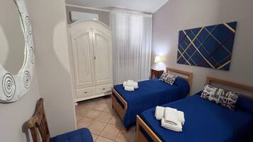 Une chambre d’hôtel avec deux lits, une armoire, un miroir, un tableau et une lampe.