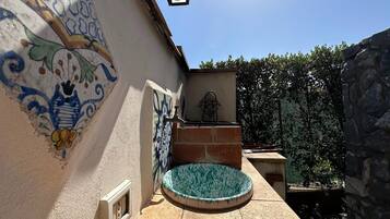 A courtyard with a tiled wall, a small pool, and a stone structure.