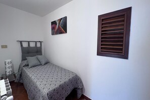 Ein Schlafzimmer mit einem Bett, einem Wandbild und einem Fenster mit Jalousien.