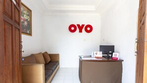 Quarto com sofá, escrivaninha e parede com as letras 'OYO' em vermelho.