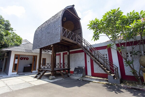 A building with a unique sloped roof structure, a staircase leading to a platform, and a small outdoor seating area.
