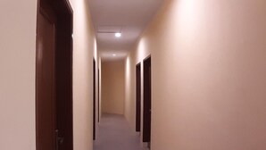 Un couloir bordé de portes des deux côtés, qui donnent accès à des pièces.