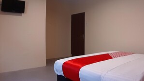 Une chambre d’hôtel avec un lit, une porte et un téléviseur fixé au mur.