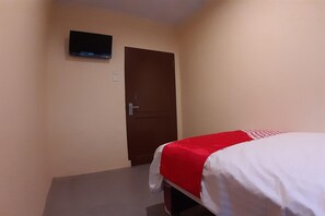 A hotel room with a bed, a door, and a TV mounted on the wall. - Comfortable Standard Single Stay (Medan)
