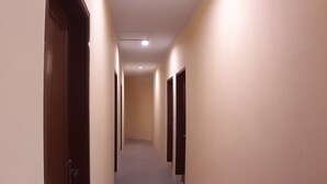 A corridor with doors on both sides, a carpeted floor, and a ceiling light. - Comfortable Standard Single Stay (Medan)