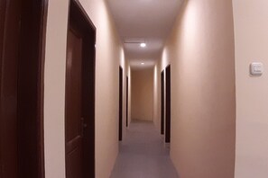 A corridor with doors on both sides, a light switch on the wall, and a ceiling light. - Comfortable Standard Single Stay (Medan)