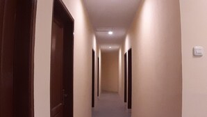 Ein Flur mit Türen auf beiden Seiten, einem Lichtschalter an der Wand und einer Deckenleuchte.