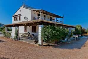 Ein zweistöckiges Haus mit Balkon, Satellitenschüssel und einem Schotterweg.