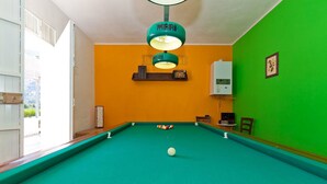 A pool table with a single white ball, a green wall, and a ceiling light fixture. - Holiday Home with pool in Sicily (Castellamare del Golfo)