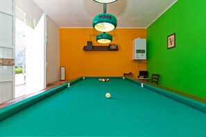 Ein Billardtisch mit einer weißen Kugel, einer grünen Wand und einer Deckenleuchte.