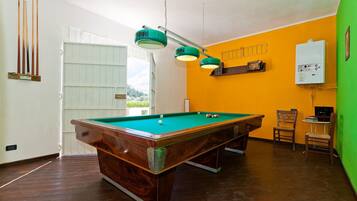 Une table de billard avec un placage en bois, un drap de jeu vert et trois lampes suspendues.