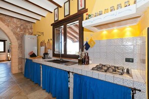 Eine Küche mit einem Steingewölbe, einem Kühlschrank, einer Spüle, einem Herd und einer blauen Tischdecke.
