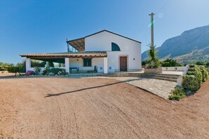 Ein eingeschossiges Haus mit geneigtem Dach, einer überdachten Veranda und einer Steintreppe, die zum Eingang führt.