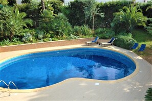 A swimming pool with a curved edge, surrounded by a brick border and a tiled deck. - Villa in Valderice with Pool and Garden (Valderice (TP))