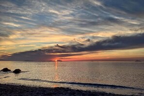 A sunset over a calm sea with a beach in the foreground. - Villa in Valderice with Pool and Garden (Valderice (TP))