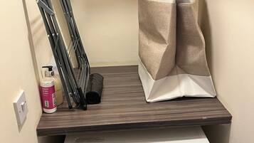 Un área de lavandería con lavadora, tendedero y una bolsa de ropa.