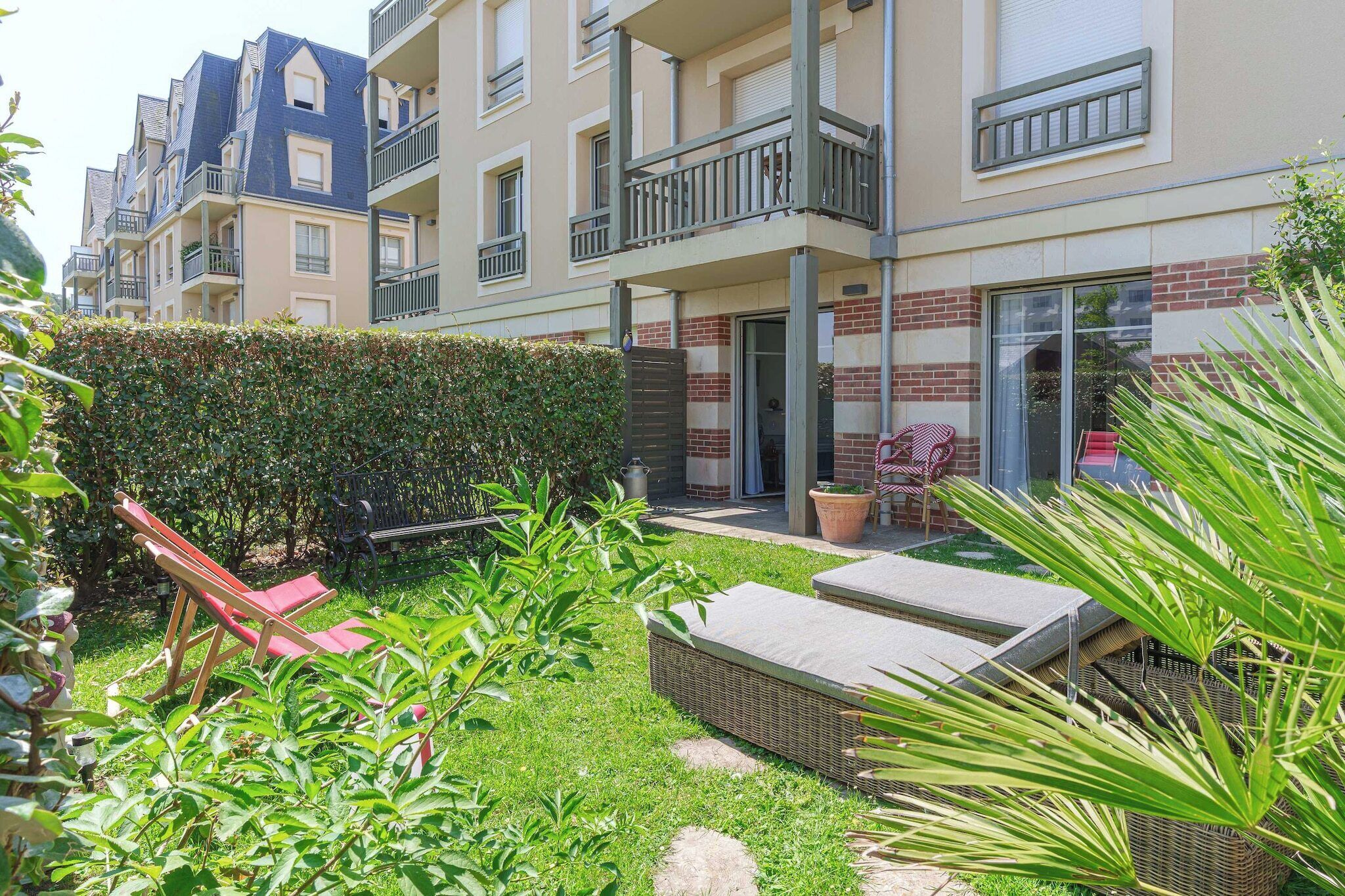 Ein Wohngebäude mit gepflegtem Garten, Außenmöbeln und einem sichtbaren Balkon.