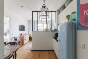 Eine moderne Küche mit einem blauen Kühlschrank, einer Pendelleuchte und Blick ins Freie.