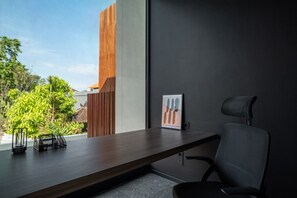 A modern office space with a dark wall, a wooden partition, a desk with a chair, and a framed picture. - Cozy 2BR Villa in Umalas | Near Seminyak & Canggu (Umalas)
