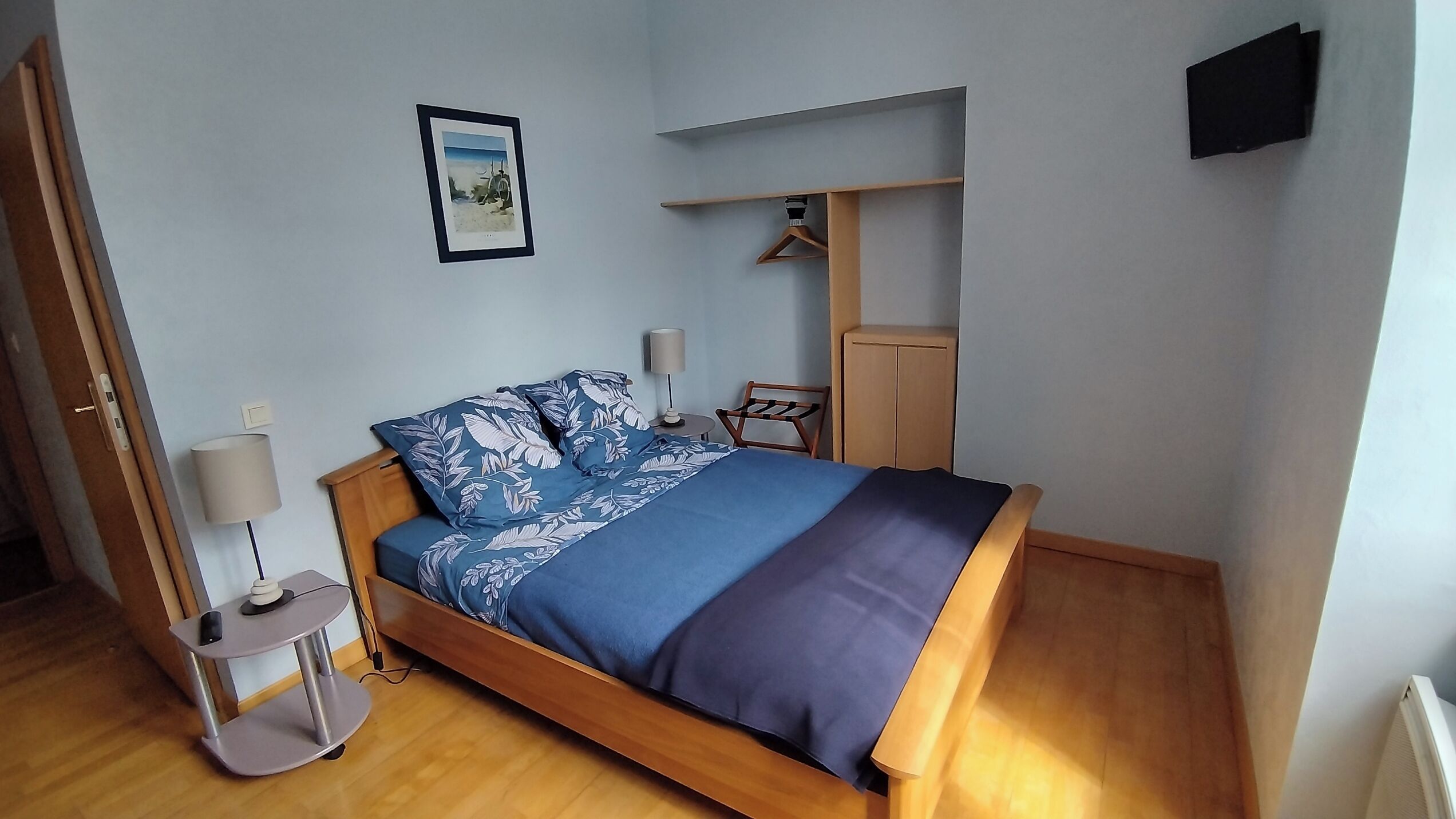 Ein Schlafzimmer mit Bett, Nachttischen, einem Kleiderschrank und einem Wandregal.