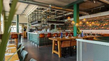 Een restaurantinterieur met een bar, zitmogelijkheden en een decoratieve wand.